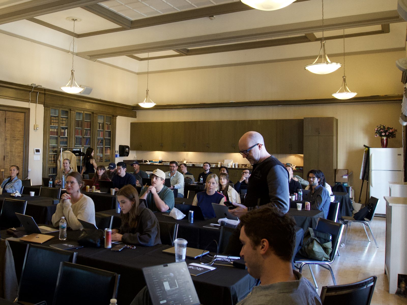 Eric Skiff checks his phone while participants work at laptops around the room
